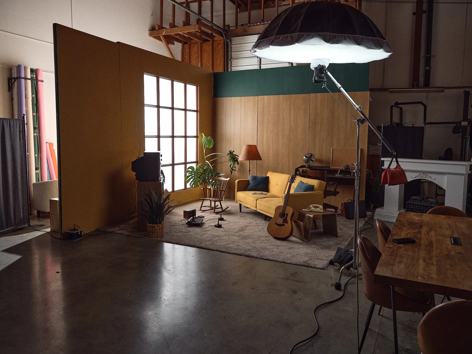 A styled living room set with a yellow sofa and overhead softbox at Cuento